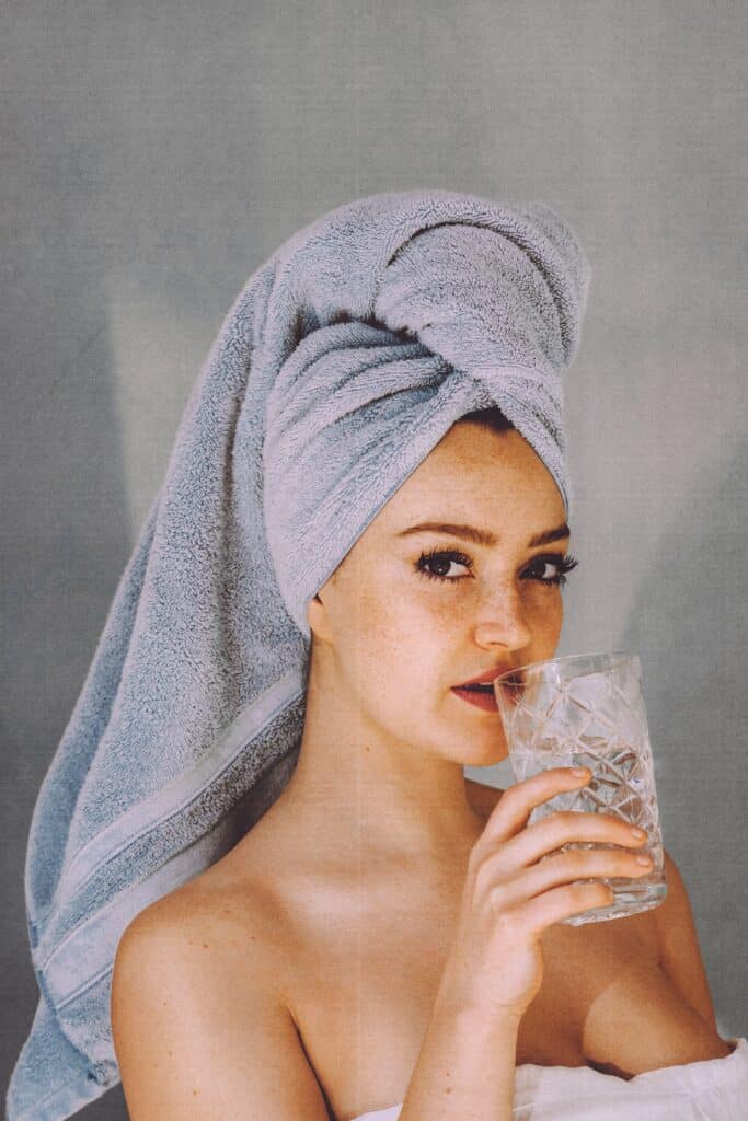lady drinking water, with towel on head
